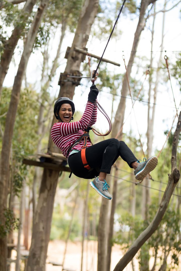 Young Woman Enjoying Zipline Adventure in Forest Ropes Course