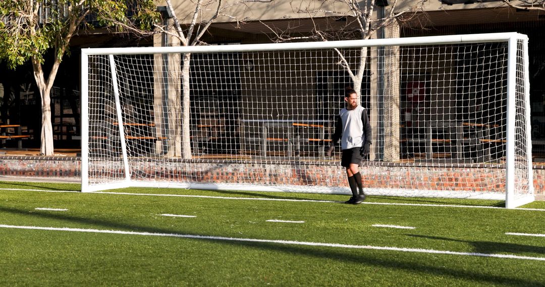 Soccer Player Standing by Goalpost on Sunny Day