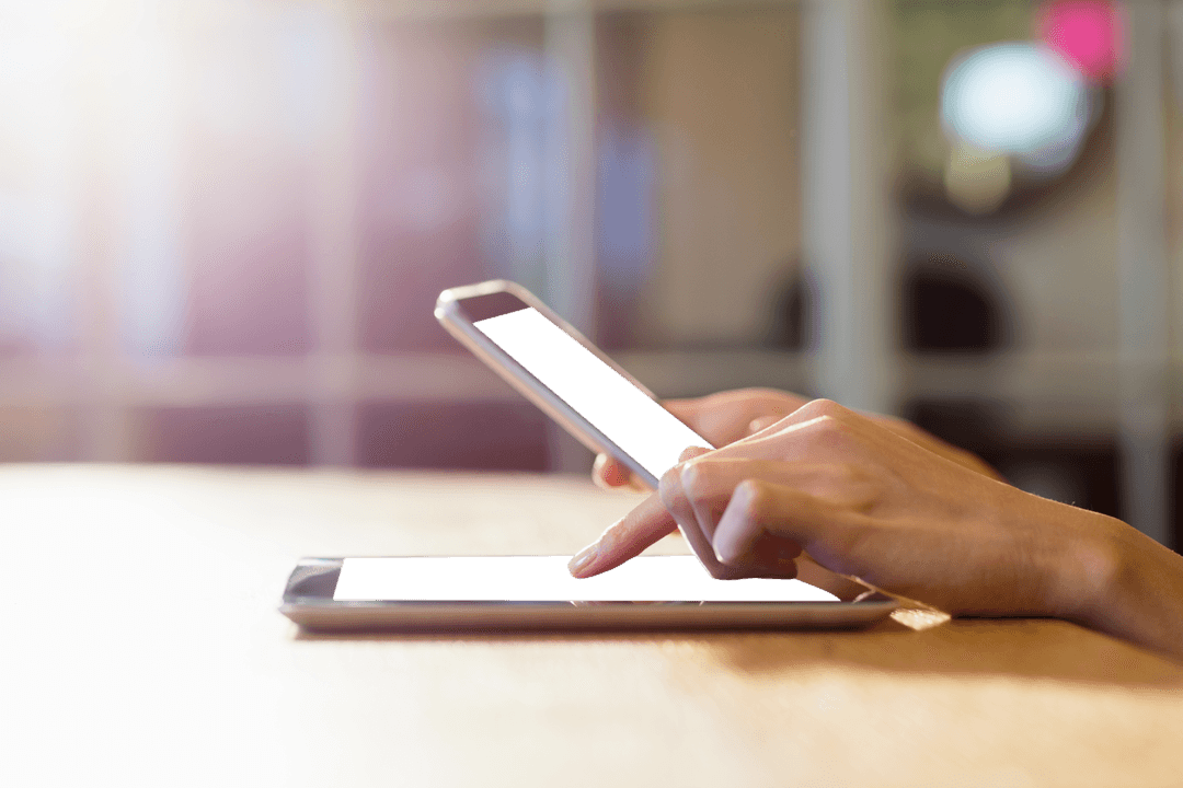 Businesswoman's Hands Using Smartphone and Tablet in Modern Office Environment