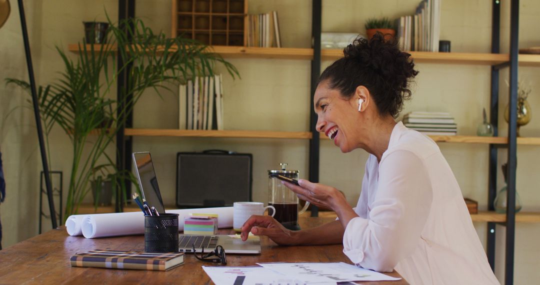 Biracial woman using laptop and talking on smartphone while working from home - Free Images, Stock Photos and Pictures on Pikwizard.com