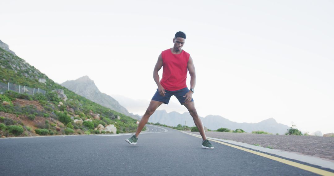 Athletic Man Stretching on Road in Mountainous Area - Free Images, Stock Photos and Pictures on Pikwizard.com