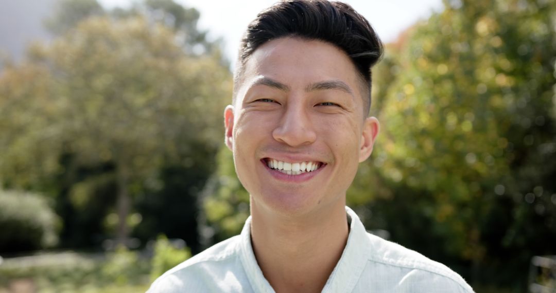 Smiling Young Asian Man in Sunny Garden