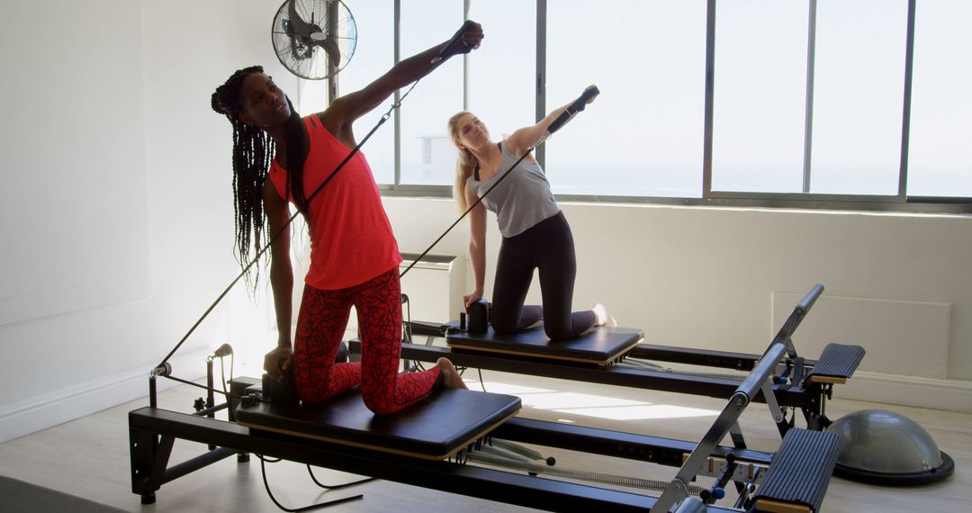 Two Women Doing Pilates Workout on Reformer Machines - Free Images, Stock Photos and Pictures on Pikwizard.com