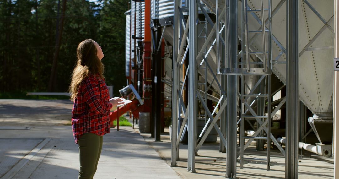 Woman Inspecting Large Industrial Silos Outdoors - Free Images, Stock Photos and Pictures on Pikwizard.com