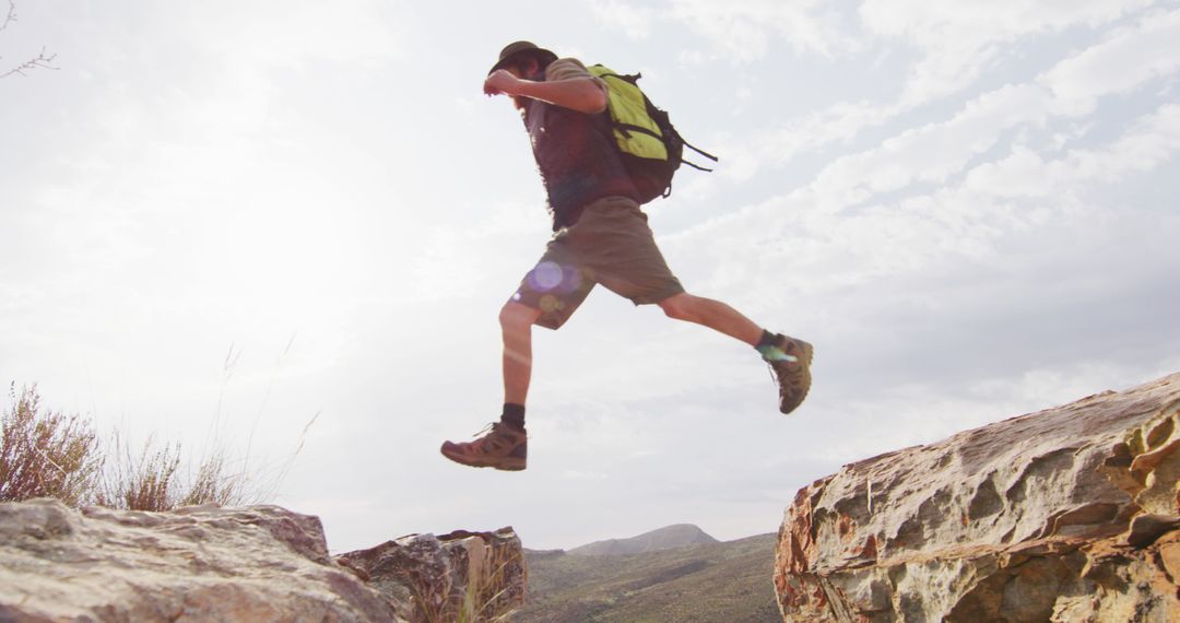 Adventurous Hiker Jumping Over Rocky Mountain Ravine