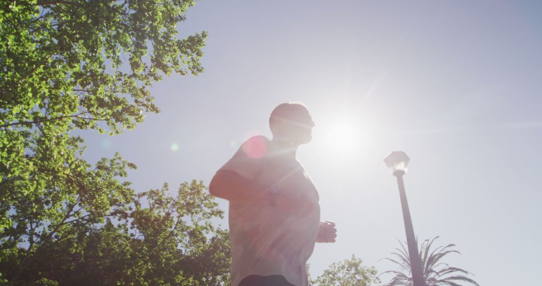 Man Jogging Outdoors in Sunlit Park - Free Images, Stock Photos and Pictures on Pikwizard.com