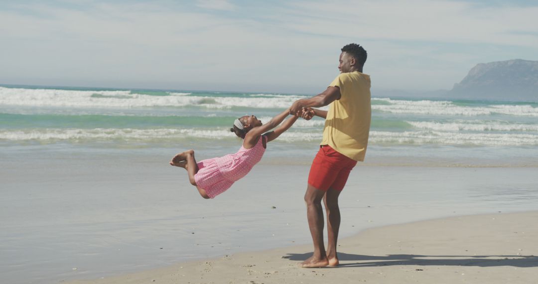 Father Spinning Daughter on Beach on Sunny Day - Free Images, Stock Photos and Pictures on Pikwizard.com