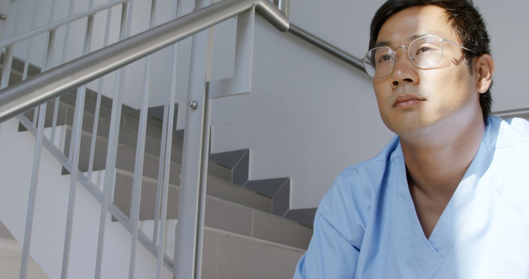 Thoughtful Medical Professional Sitting on Staircase during Break - Free Images, Stock Photos and Pictures on Pikwizard.com