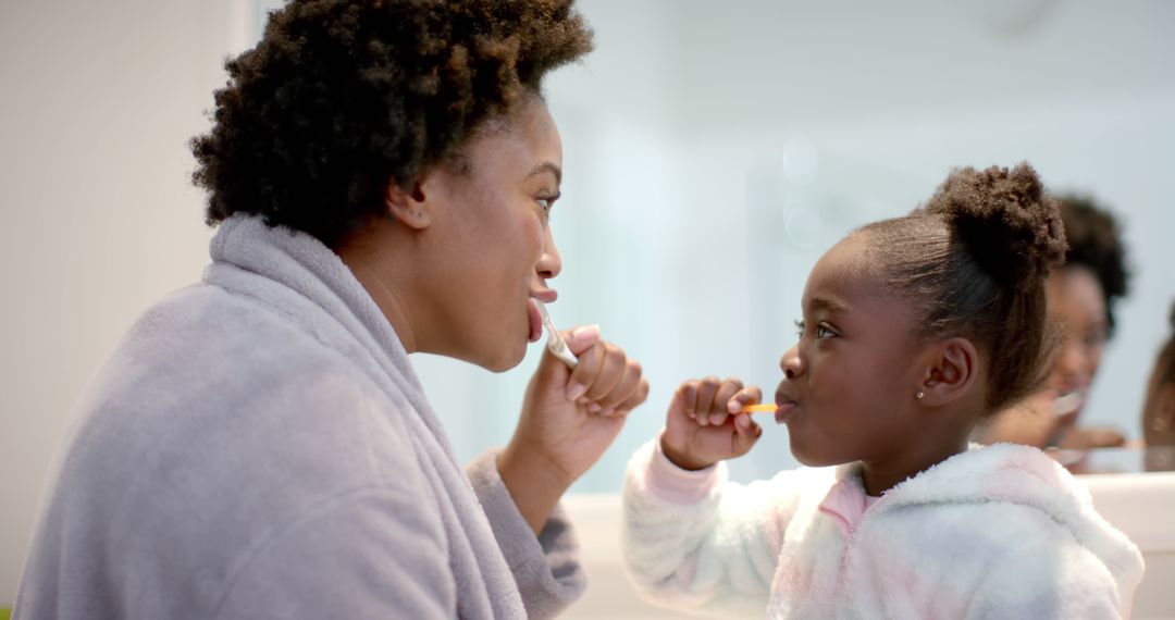 African American Mother and Daughter Brushing Teeth Together in Bright Bathroom - Free Images, Stock Photos and Pictures on Pikwizard.com