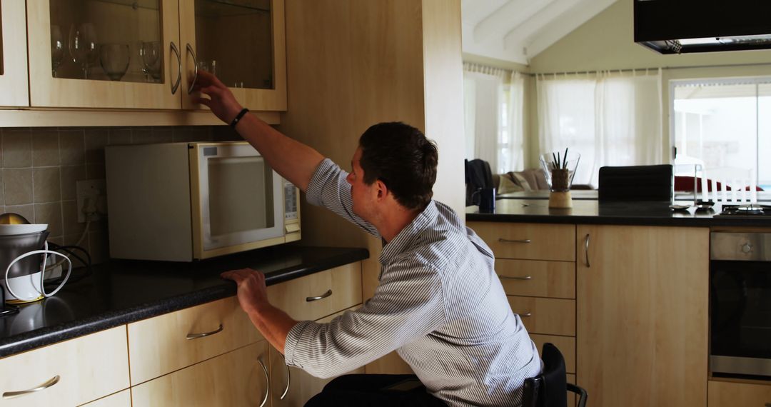 Man in Wheelchair Reaching for Kitchen Cabinet - Free Images, Stock Photos and Pictures on Pikwizard.com