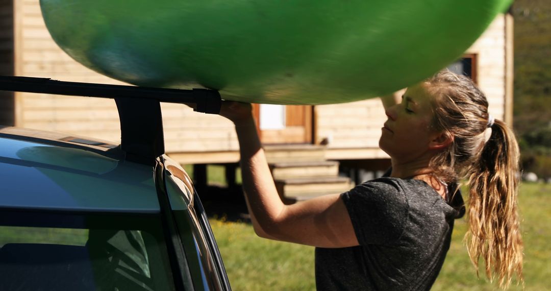 Woman Loading Kayak onto Car Roof Near Wooden Cabin - Free Images, Stock Photos and Pictures on Pikwizard.com