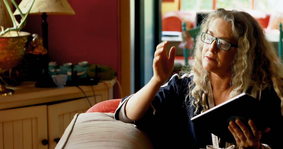 Senior Woman Reading Book and Gesturing at Home - Free Images, Stock Photos and Pictures on Pikwizard.com