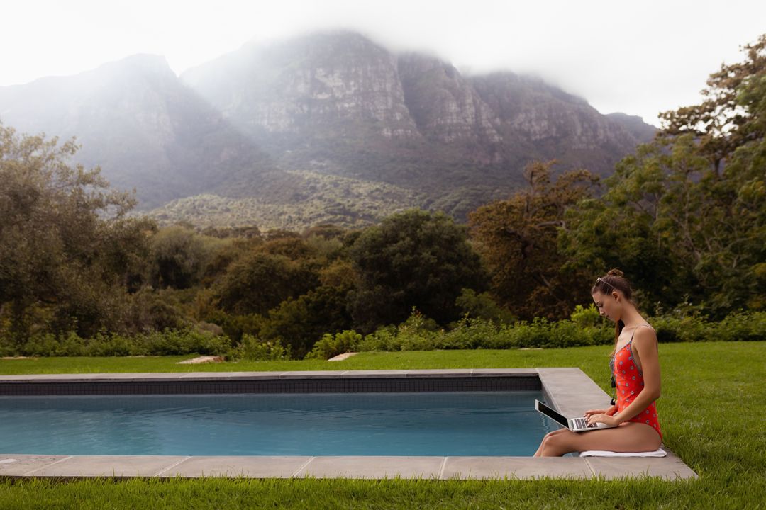 Woman in Swimwear Using Laptop by Poolside with Mountain View - Free Images, Stock Photos and Pictures on Pikwizard.com
