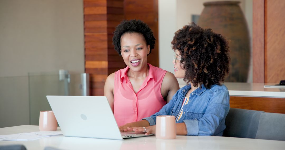 Diverse women collaborating on laptop at home office