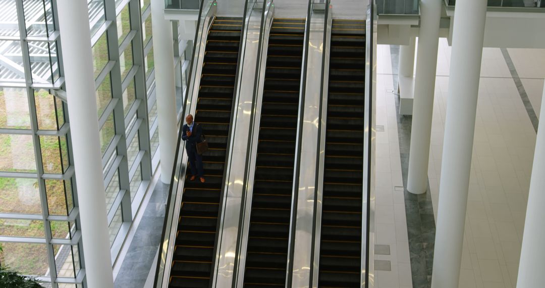 Businessman Standing on Escalator in Modern Office Building - Free Images, Stock Photos and Pictures on Pikwizard.com