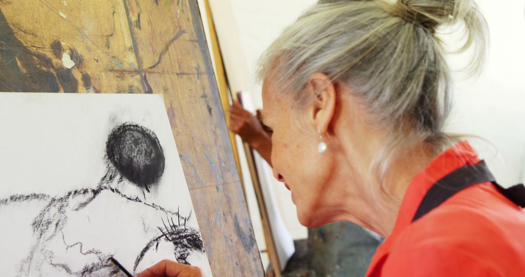 Older Woman Focuses on Drawing with Charcoal - Free Images, Stock Photos and Pictures on Pikwizard.com