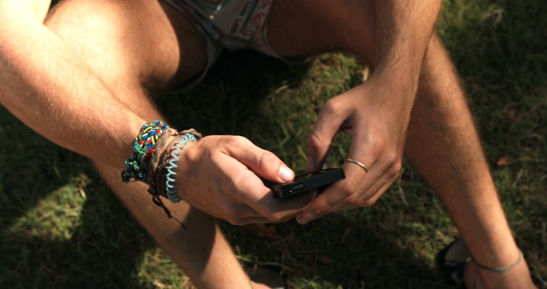 Young Man Texting Outdoors Wearing Bracelets - Free Images, Stock Photos and Pictures on Pikwizard.com