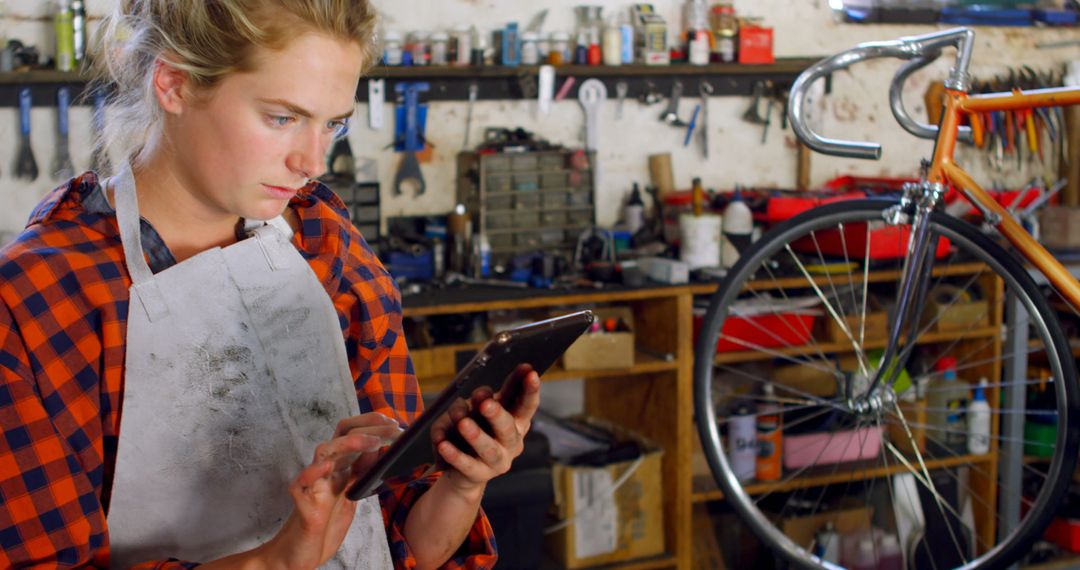 Young Female Mechanic Using Tablet in Bicycle Repair Workshop - Free Images, Stock Photos and Pictures on Pikwizard.com