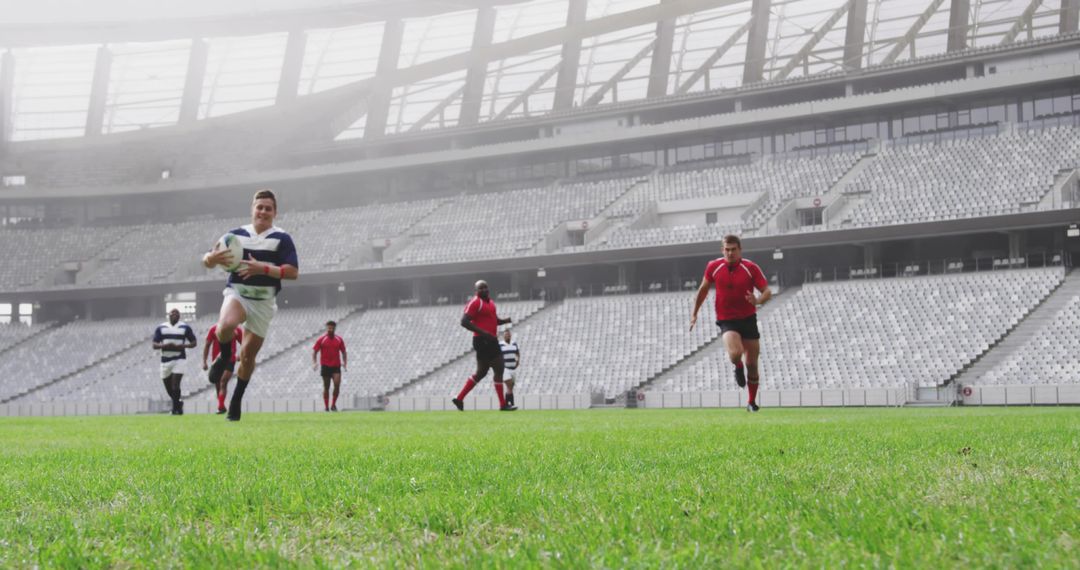 Rugby player sprinting with ball toward try line in modern stadium while opponents chasing