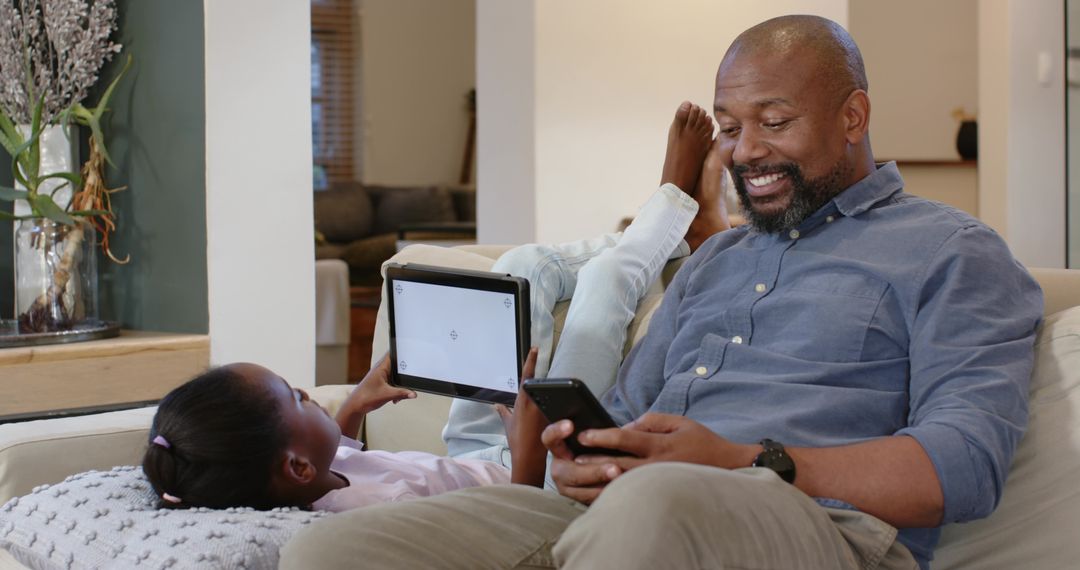 Father and Daughter Enjoying Quality Time with Gadgets at Home