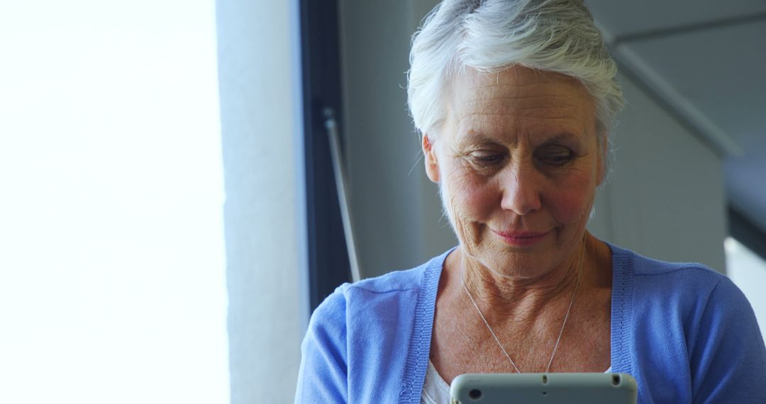 A senior Caucasian woman is focused on her tablet, with copy space - Free Images, Stock Photos and Pictures on Pikwizard.com