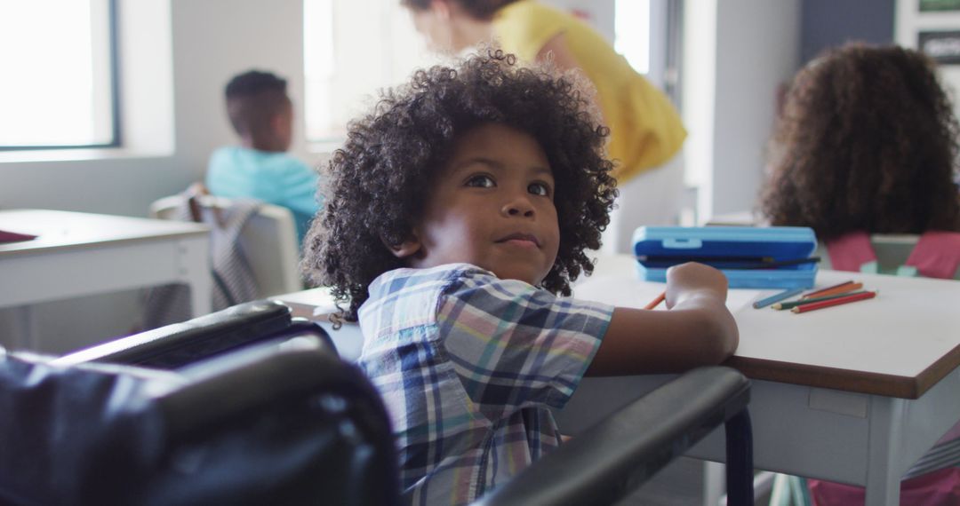 Image of happy disabled african american boy sitting at desk in classroom - Free Images, Stock Photos and Pictures on Pikwizard.com