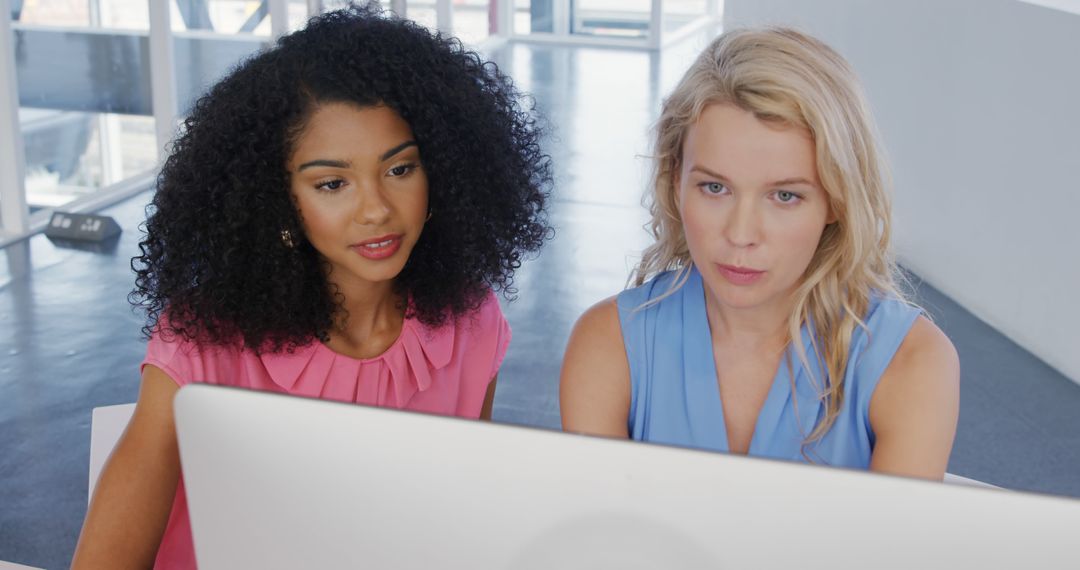 Two Women Collaborating on Computer in Modern Office Setting - Free Images, Stock Photos and Pictures on Pikwizard.com