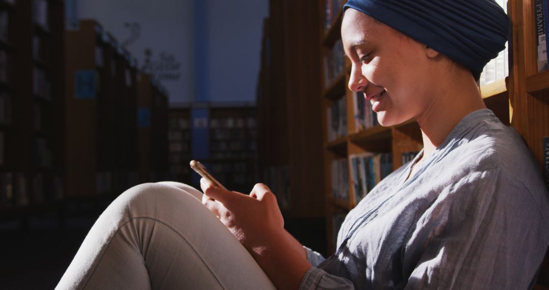 Young Woman Smiling While Using Smartphone in Library - Free Images, Stock Photos and Pictures on Pikwizard.com