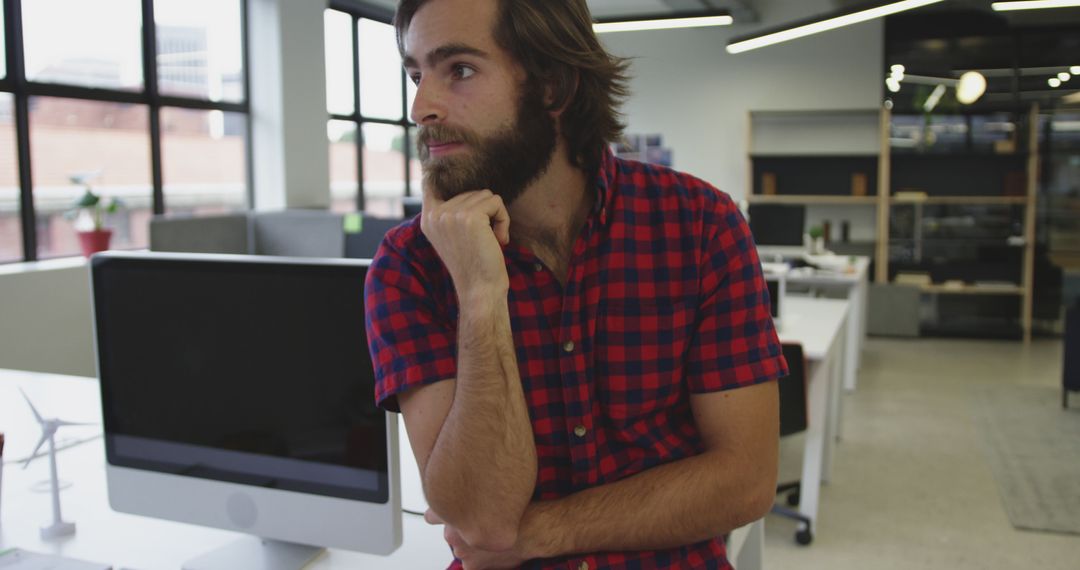 Pensive Bearded Man in Plaid Shirt Reflecting in Modern Office - Free Images, Stock Photos and Pictures on Pikwizard.com