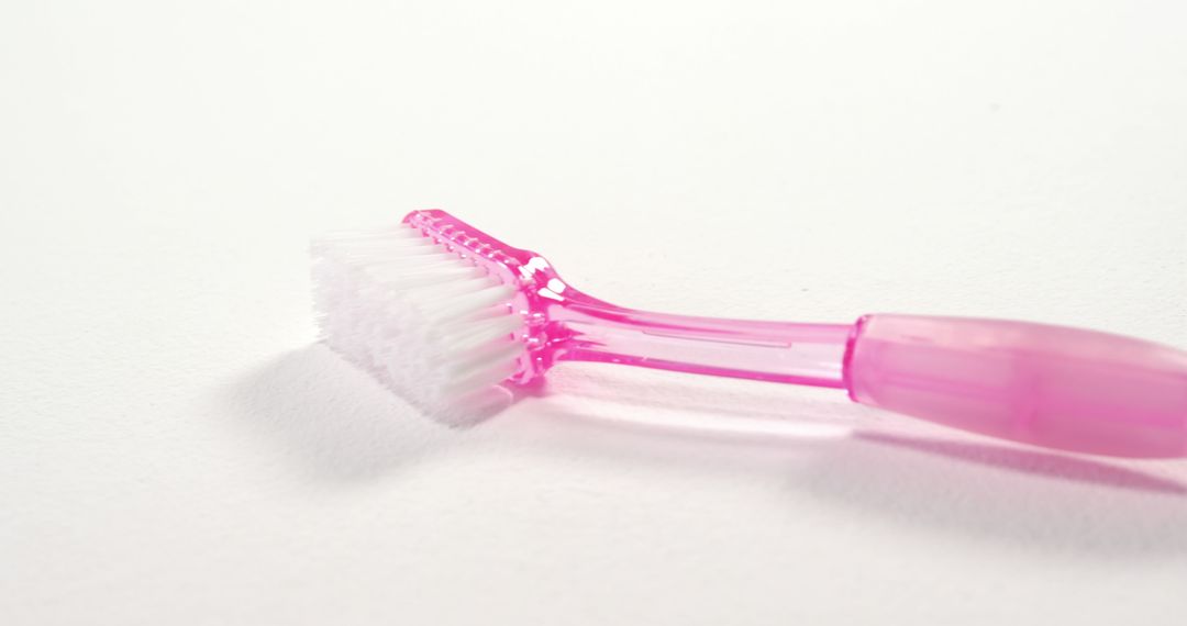 A pink toothbrush lies on a white background, with copy space - Free Images, Stock Photos and Pictures on Pikwizard.com