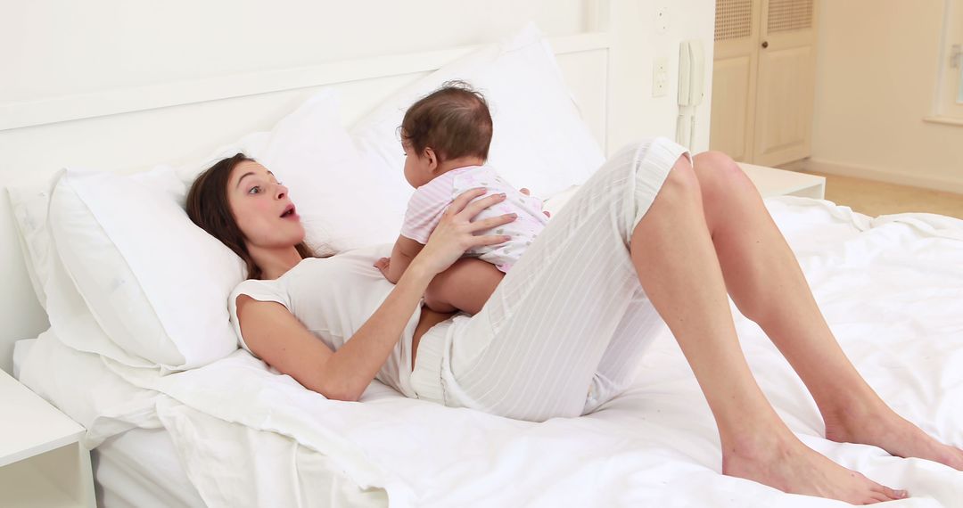 Mother Enjoying Playtime with Baby on White Bed - Free Images, Stock Photos and Pictures on Pikwizard.com