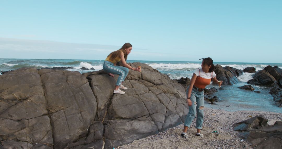 Young Women Exploring Rocky Beach on Sunny Day - Free Images, Stock Photos and Pictures on Pikwizard.com