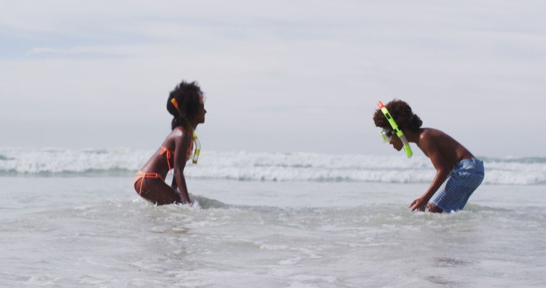 African american children wearing scuba goggles playing at the beach - Free Images, Stock Photos and Pictures on Pikwizard.com