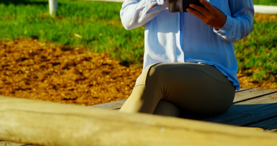 Person Sitting Outdoors Reading Using Mobile Tablet in Garden - Free Images, Stock Photos and Pictures on Pikwizard.com