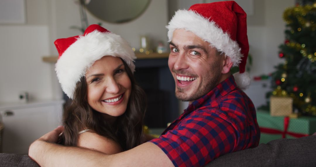 Happy Couple Celebrating Christmas at Home with Santa Hats - Free Images, Stock Photos and Pictures on Pikwizard.com