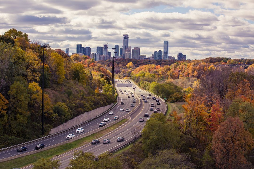 Aerial View of Highway Amidst Autumn Foliage Leading to City Skyline - Free Images, Stock Photos and Pictures on Pikwizard.com