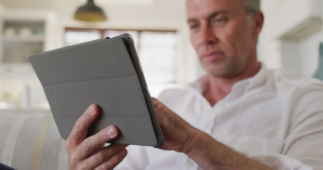 Mature Man Using Tablet at Home for Reading - Free Images, Stock Photos and Pictures on Pikwizard.com