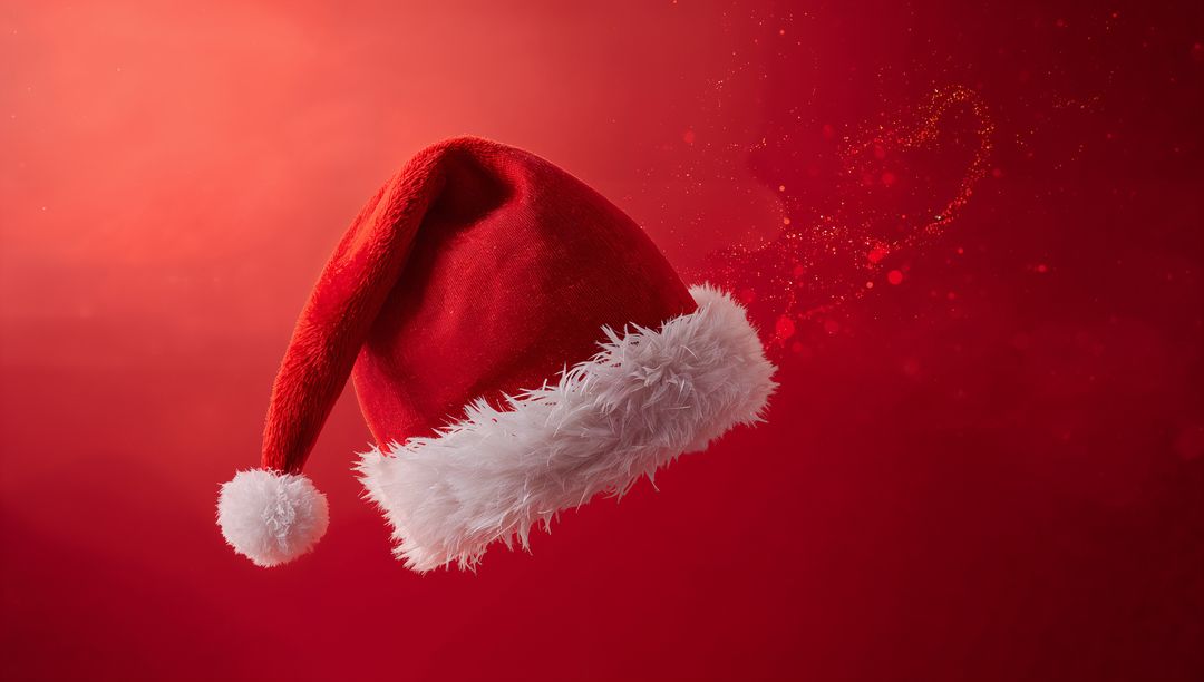 Floating Santa hat with faux-fur trim and trailing gold glitter on red gradient with festive lights