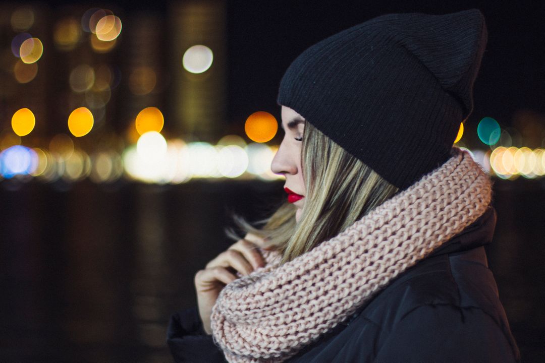 Thoughtful Woman Wearing Knit Scarf Under City Lights - Free Images, Stock Photos and Pictures on Pikwizard.com