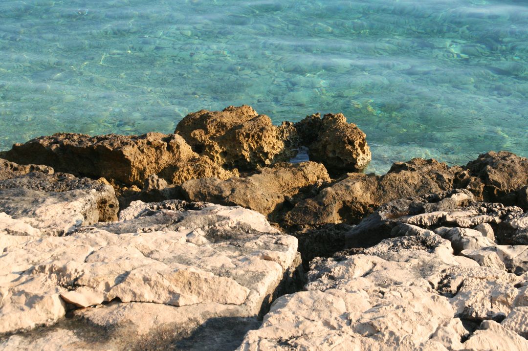 Rocky Shoreline with Clear Blue Water on Sunny Day - Free Images, Stock Photos and Pictures on Pikwizard.com