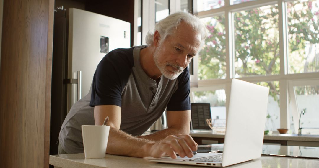 Senior Man Using Laptop in Kitchen with Coffee Mug - Free Images, Stock Photos and Pictures on Pikwizard.com