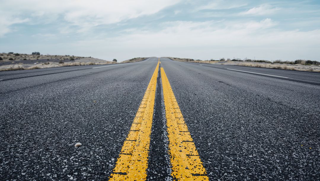 Stretching empty desert highway with leading double yellow lines and open horizon