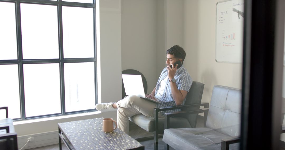 Business Professional Combining Phone Call and Laptop Use in Modern Office