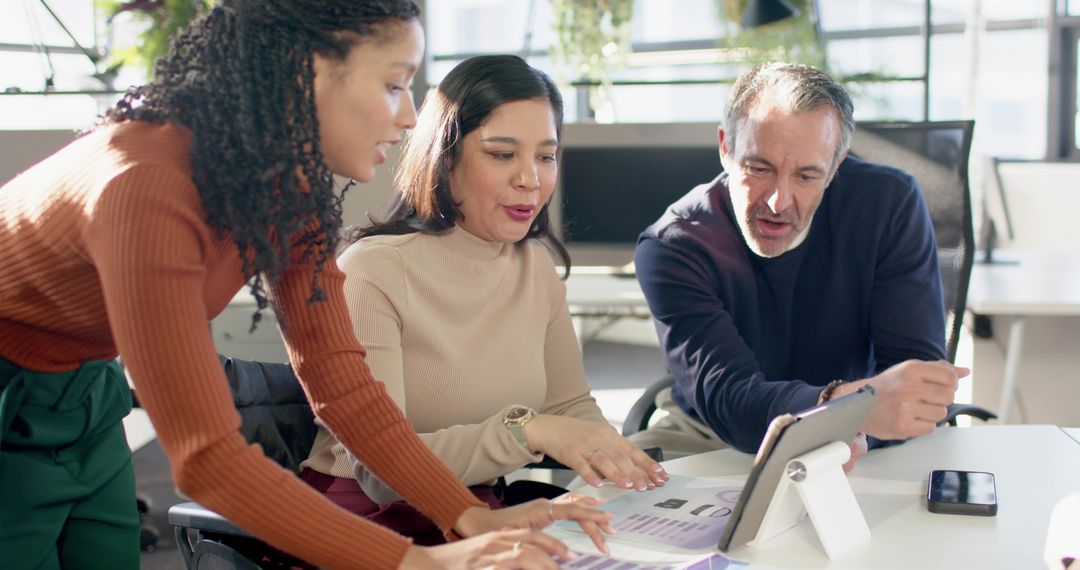 Multicultural Team Collaborating Over Charts and Tablet in Bright Modern Office