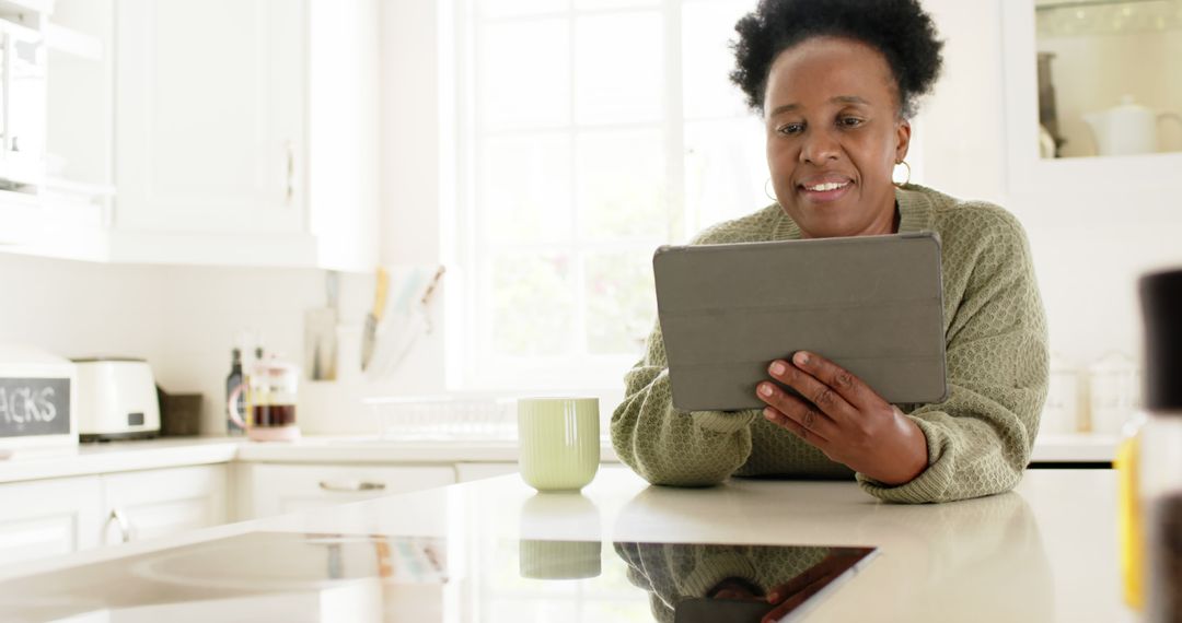 Mature woman using digital tablet in modern kitchen - Free Images, Stock Photos and Pictures on Pikwizard.com