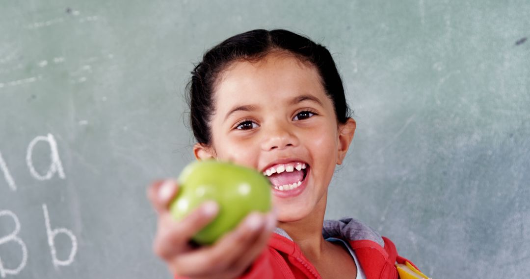 Young Girl Holding Green Apple in Classroom - Free Images, Stock Photos and Pictures on Pikwizard.com