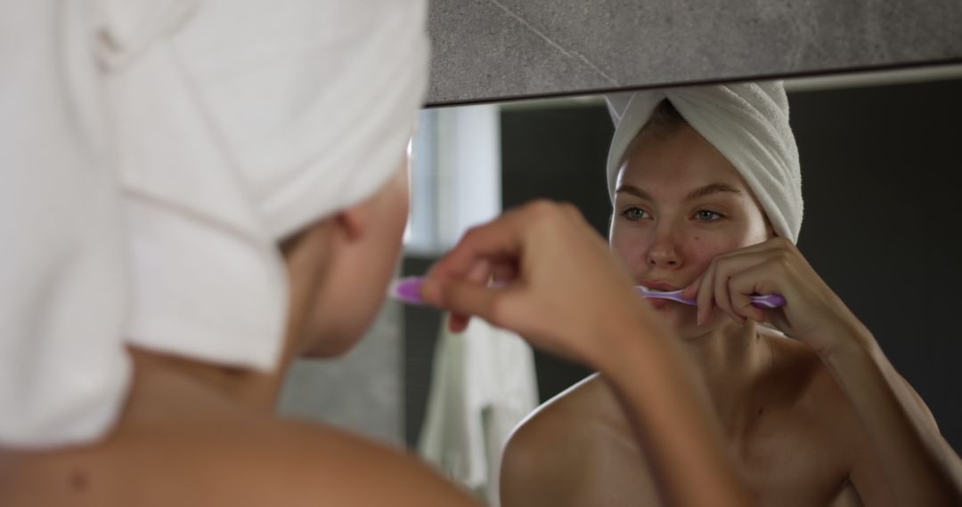 Woman Brushing Teeth in Bathroom Mirror with Towel on Head - Free Images, Stock Photos and Pictures on Pikwizard.com