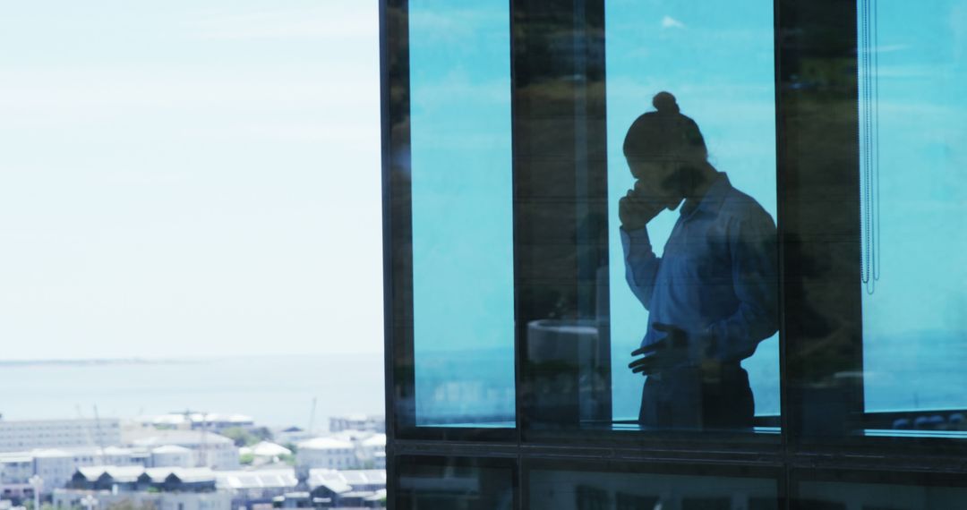 Silhouette of Person Talking on Phone in Modern Office with City View - Free Images, Stock Photos and Pictures on Pikwizard.com