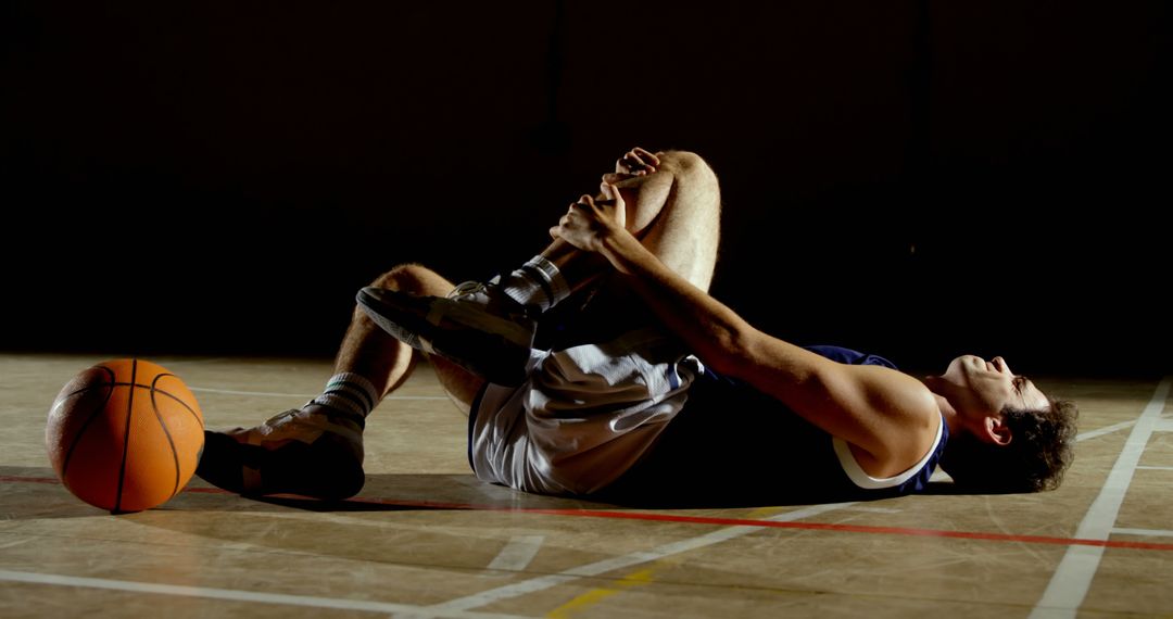 Injured Basketball Player Lying on Court Holding Knee - Free Images, Stock Photos and Pictures on Pikwizard.com