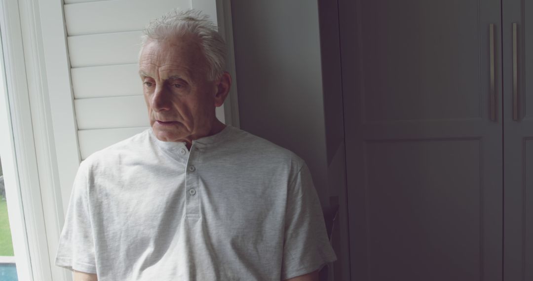 Elderly Man With Pensive Expression Standing By Window - Free Images, Stock Photos and Pictures on Pikwizard.com